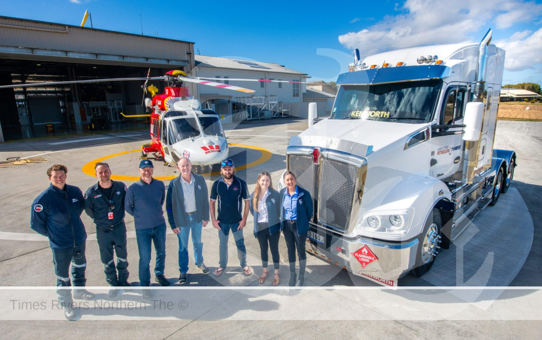Group of people standing in front of a truck and a wetspac helicopter