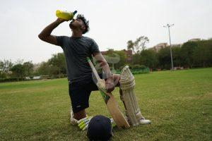 Cricket player drinking water due high body temperature in hot weather.