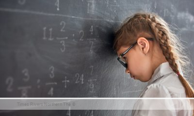 A child with her head against a chalk board struggling with Dyscalculia