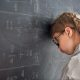 A child with her head against a chalk board struggling with Dyscalculia