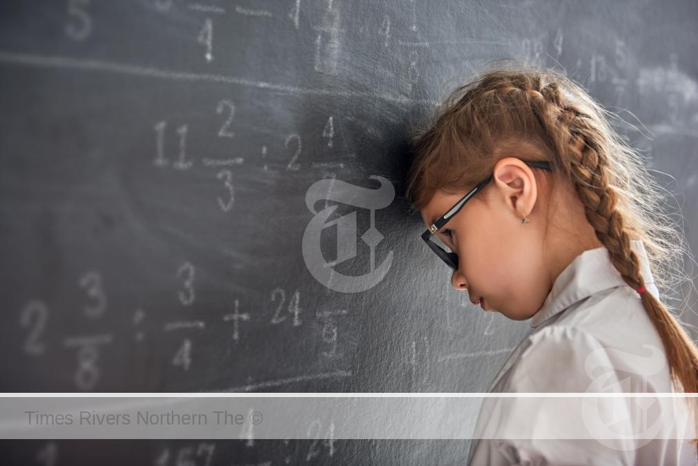 A child with her head against a chalk board struggling with Dyscalculia