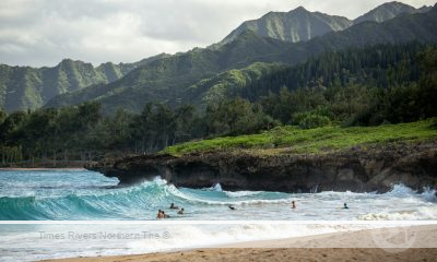 A beach in Hawaii with mountains in the background