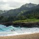 A beach in Hawaii with mountains in the background